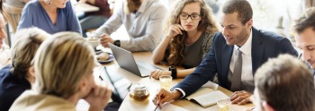 Geschäftsleute sitzen bei einem Meeting um einen Tisch