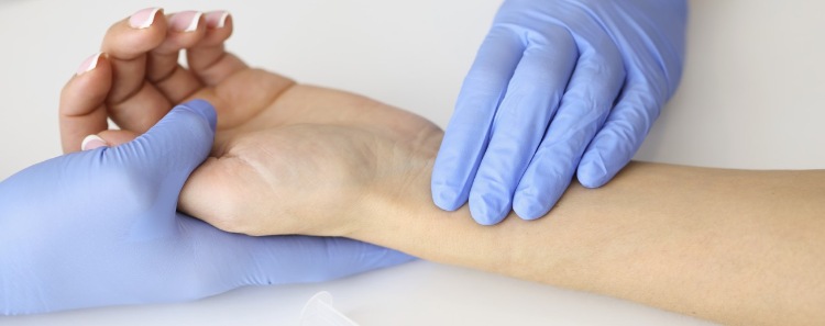 Arzt misst mit Handschuhen den Puls eines Kranken