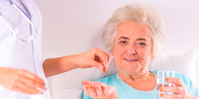 Patientin erhält Medikamente im Bett liegend