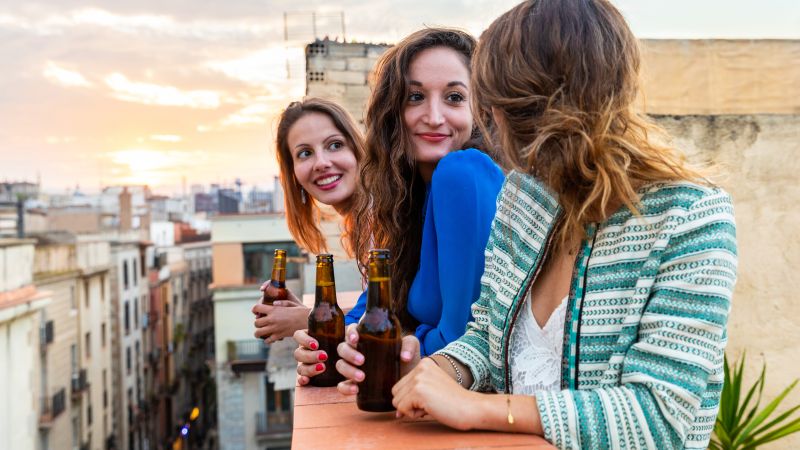 Frauen feiern auf dem Balkon mit einem Bier