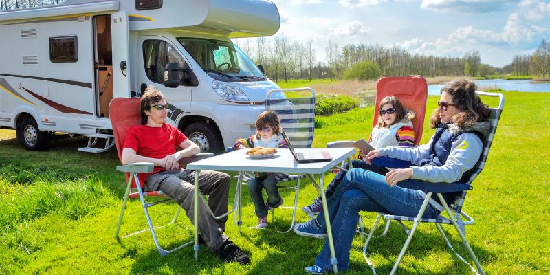 Familie in den Ferien sitzt vor einem Wohnmobil