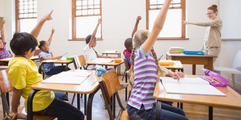 Kinder in einer Schulklasse melden sich