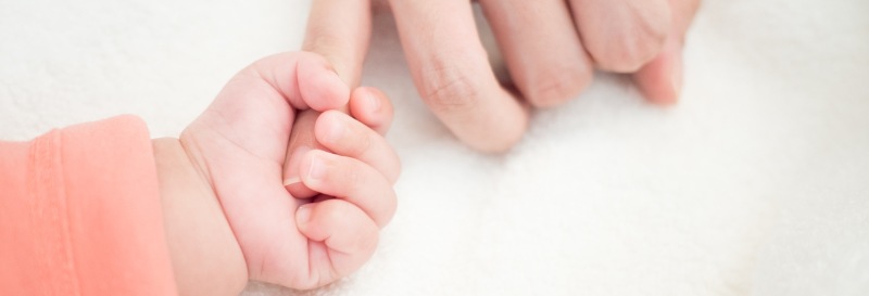 Baby greift nach Hand der Mutter