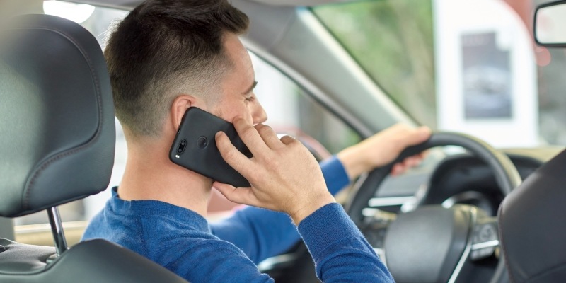 Handy am Steuer, junger Mann telefoniert während der Autofahrt