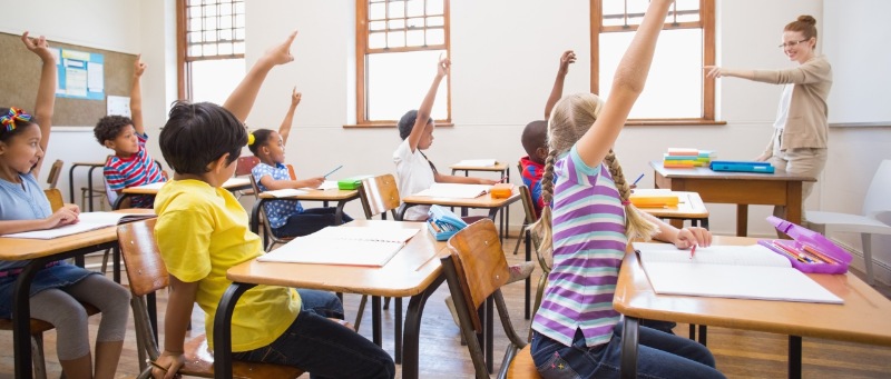 Kinder in einer Schulklasse melden sich