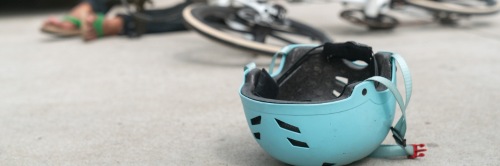 Blauer Fahrradhelm liegt auf der Straße nach einem Unfall