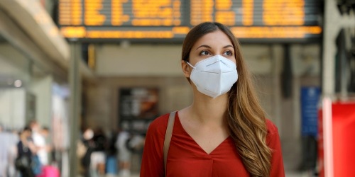 Reisende mit KN95 Maske an einem Bahnhof