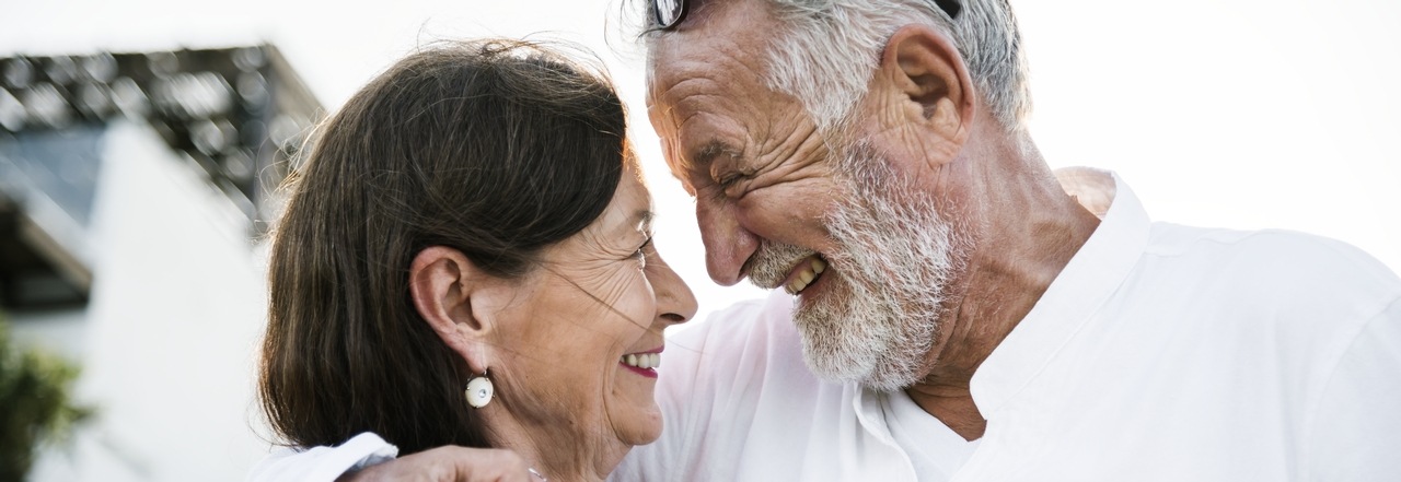 älteres Ehepaar hält sich lachend im Arm