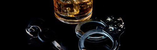 Symbolbild alkoholisiert Auto fahren mit Schnapps und Handschellen