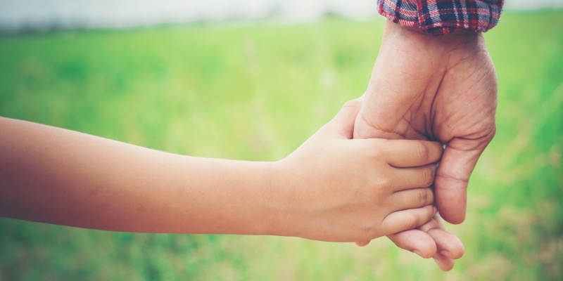 Kind und Vater halten sich an der Hand