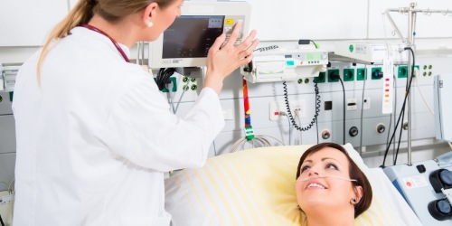 Intensivkrankenschwester steht am Bett einer Patientin