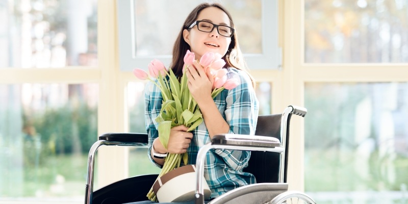 Frau im Rollstuhl freut sich über Blumen