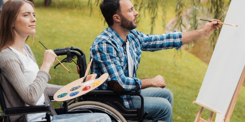 zwei Rollstuhlfahrer malen auf eine Leinwand