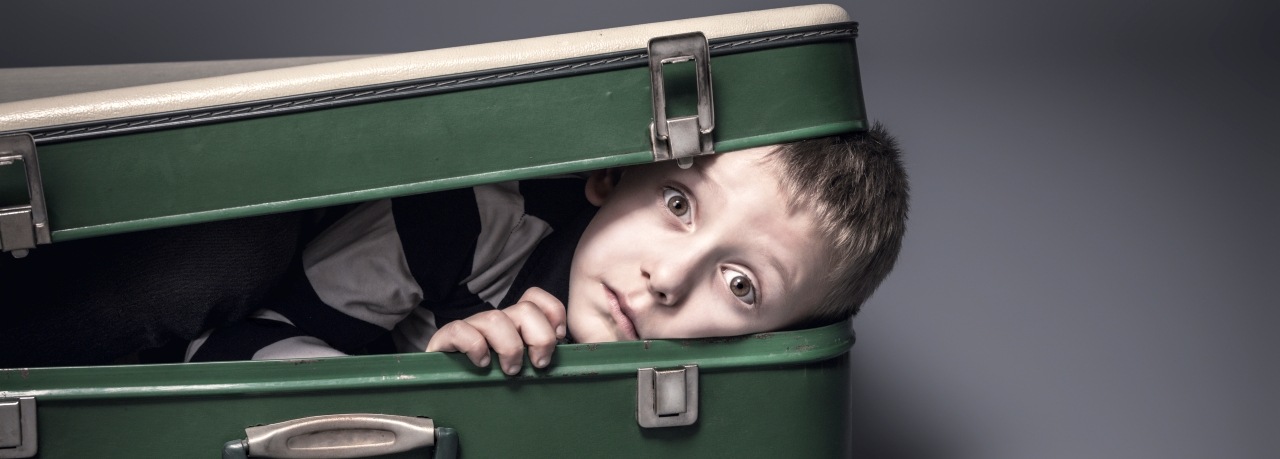 kleiner Junge versteckt sich in einem Koffer