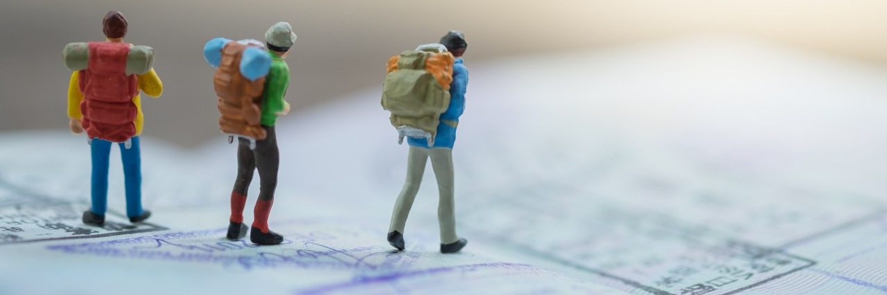 Figuren mit Rucksäcken auf einem Reisepass