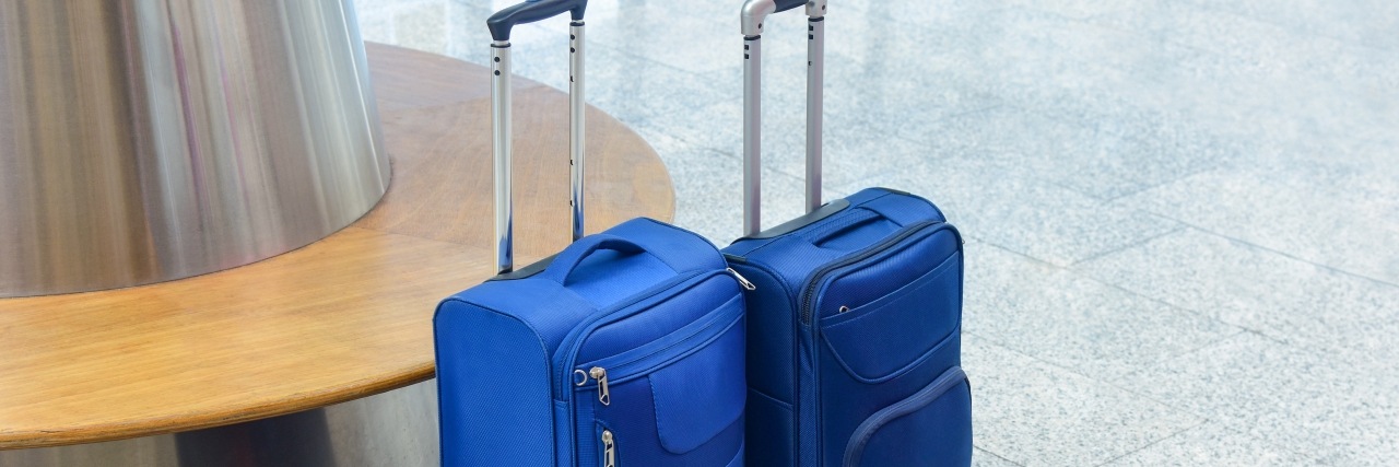 zwei kleine blaue Koffer stehen in der Flughafen Wartehalle