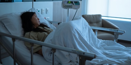 kranke Frau liegt im Krankenhausbett