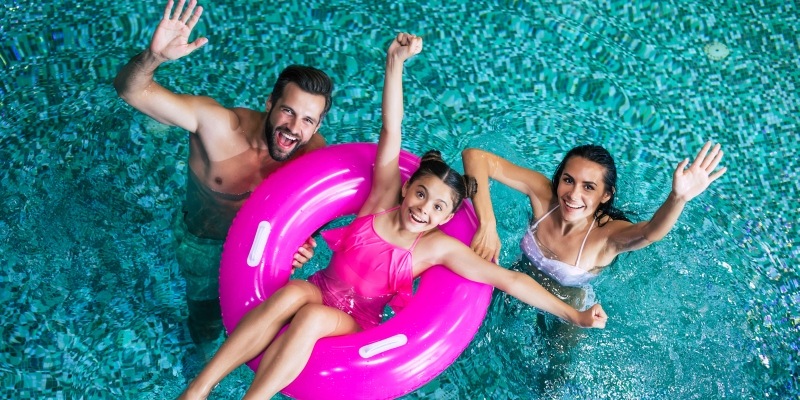 junge Familie winkt aus dem Swimmingpool