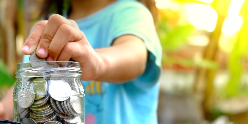 Kind sammelt Münzen in einem Marmeladeglas