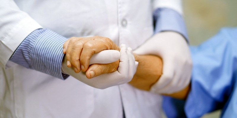 Doktor hält die Hand einer Seniorin