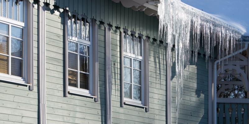 Schwere Eiszapfen hängen an einem Gebäude von der Dachrinne